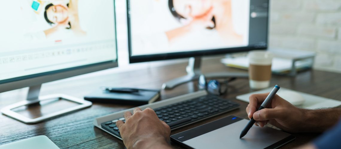 Hands of freelance editor using graphics tablet while editing photos from home